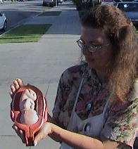 Terri Palmquist holds model of baby in the womb outside Bakersfield FPA abortion center